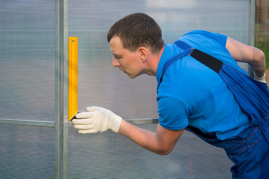 trabajador revisando las paredes de un invernadero