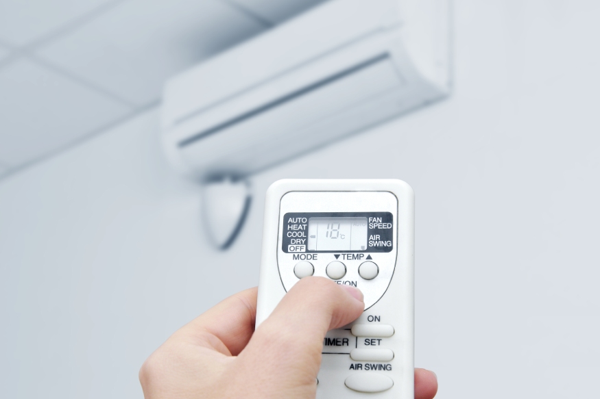Una persona ajustando la temperatura de una unidad de aire acondicionado.