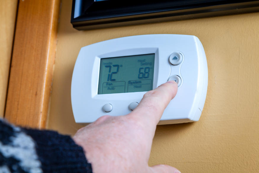 Una persona baja la temperatura en un termostato digital doméstico
