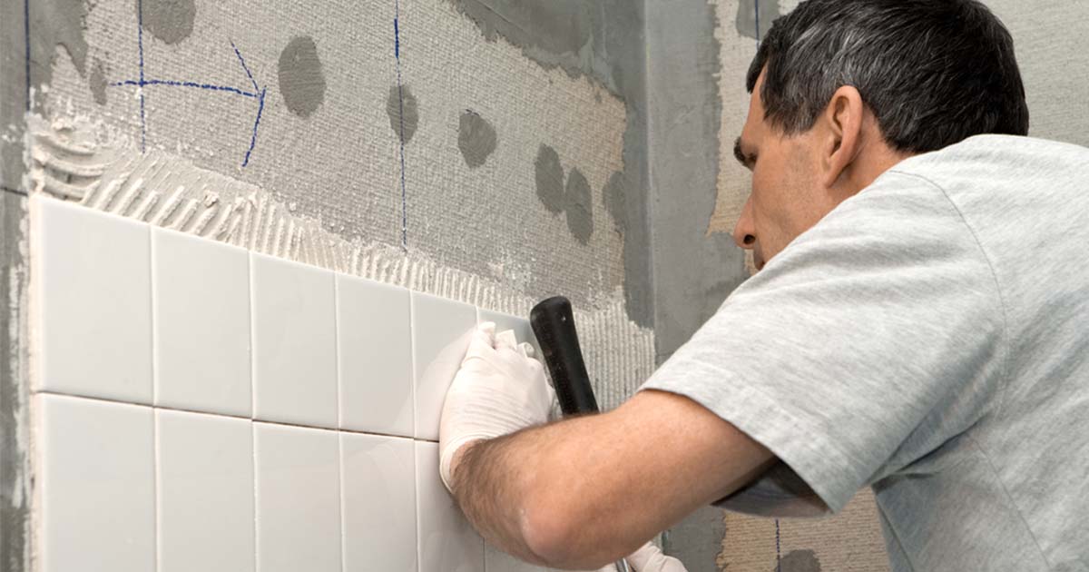 hombre instalando azulejos de baño en la pared